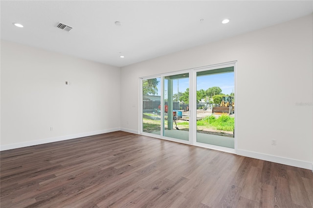 spare room featuring wood finished floors, visible vents, and baseboards