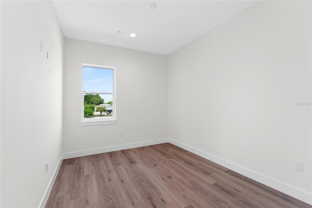 empty room with baseboards, wood finished floors, and recessed lighting