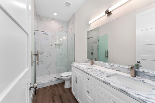 bathroom featuring a marble finish shower, visible vents, a sink, and wood finished floors