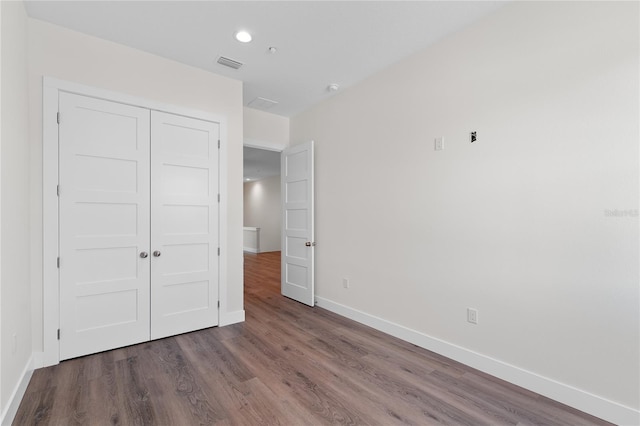 unfurnished bedroom featuring recessed lighting, a closet, visible vents, wood finished floors, and baseboards