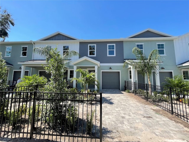 view of front of home featuring a garage, fence, and decorative driveway