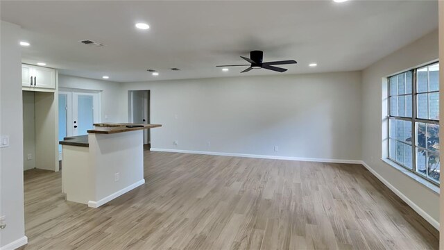 kitchen with plenty of natural light, ceiling fan, white cabinetry, and light hardwood / wood-style flooring