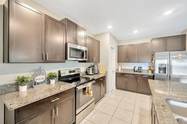 kitchen featuring light stone counters, stainless steel appliances, and light tile patterned flooring