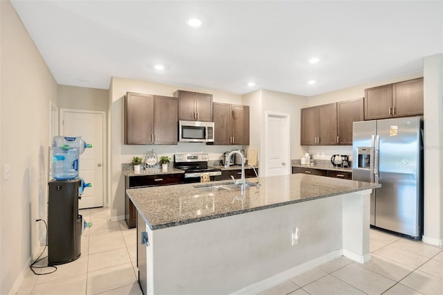 kitchen with appliances with stainless steel finishes, a kitchen island with sink, sink, and light tile patterned floors