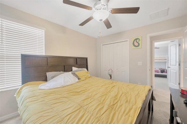 bedroom with ceiling fan, light colored carpet, and a closet