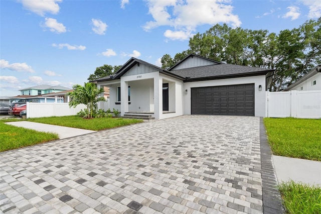 view of front of property featuring a garage, a shingled roof, decorative driveway, and fence