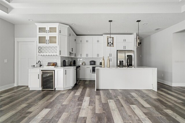 kitchen with wine cooler, white cabinetry, light countertops, hanging light fixtures, and glass insert cabinets