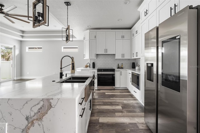 kitchen with light stone countertops, white cabinetry, appliances with stainless steel finishes, decorative backsplash, and pendant lighting