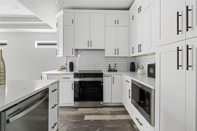 kitchen with decorative backsplash, appliances with stainless steel finishes, dark wood-style flooring, light stone countertops, and white cabinetry