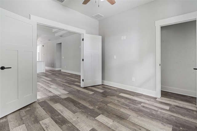 empty room featuring visible vents, dark wood-style flooring, a ceiling fan, and baseboards