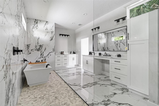 bathroom featuring stone wall, marble finish floor, a textured ceiling, and vanity