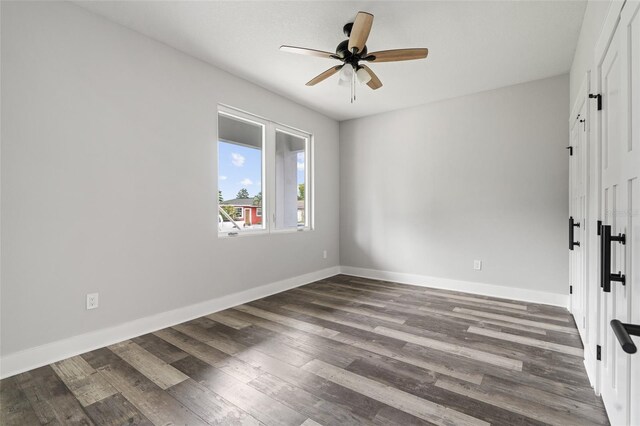 empty room featuring dark wood-style floors, baseboards, and a ceiling fan