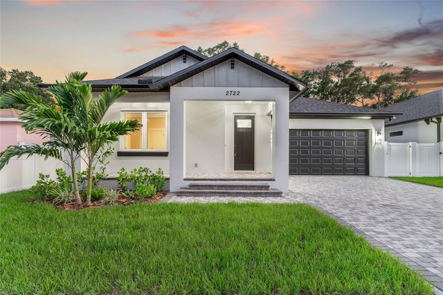 view of front of house featuring a garage, roof with shingles, decorative driveway, a front lawn, and stucco siding