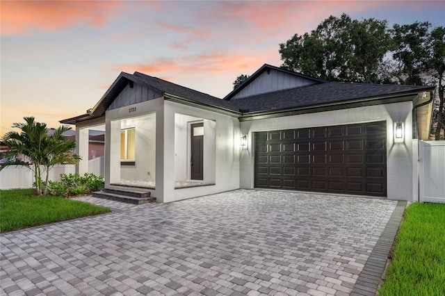 view of front of house featuring a garage, a shingled roof, decorative driveway, and fence