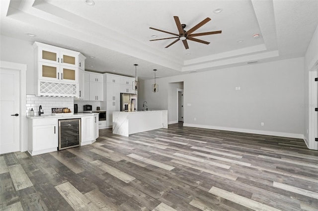 kitchen featuring light countertops, a tray ceiling, stainless steel fridge, and white cabinetry