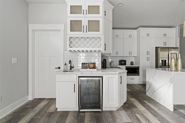 kitchen with stainless steel appliances, glass insert cabinets, white cabinetry, light stone countertops, and beverage cooler