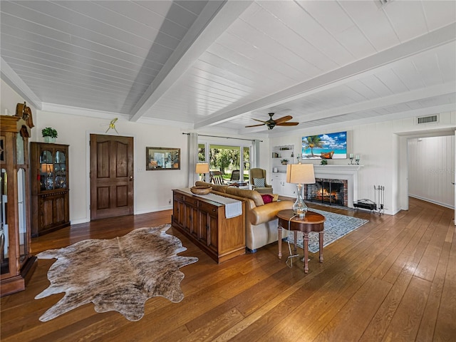 living room with ceiling fan, a fireplace, wood-type flooring, and beamed ceiling