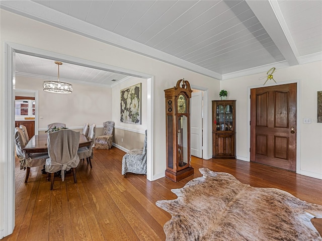 dining space with beamed ceiling, ornamental molding, hardwood / wood-style floors, and a notable chandelier