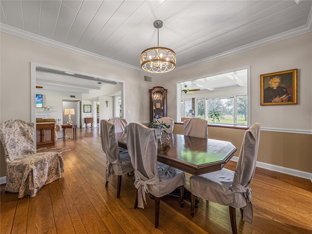 dining area with hardwood / wood-style flooring, crown molding, and an inviting chandelier