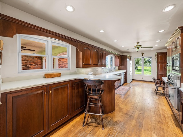 kitchen with light hardwood / wood-style floors, kitchen peninsula, sink, a breakfast bar area, and stainless steel appliances