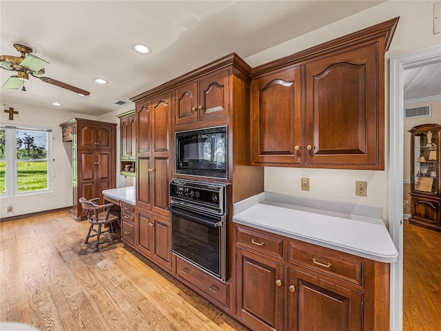 kitchen featuring ceiling fan, built in desk, light hardwood / wood-style floors, and black appliances