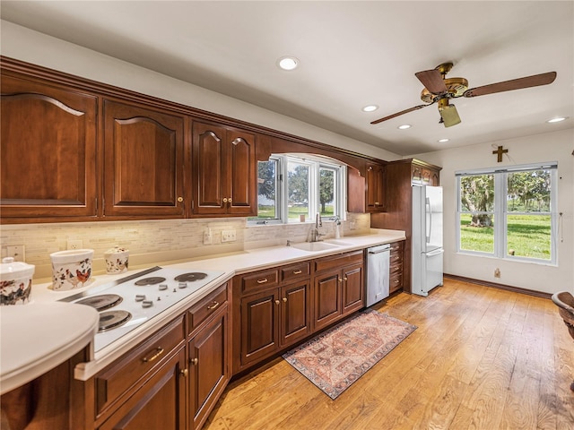 kitchen featuring tasteful backsplash, ceiling fan, sink, white appliances, and light hardwood / wood-style flooring