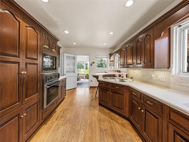 kitchen featuring wall oven, backsplash, white electric cooktop, black microwave, and light hardwood / wood-style flooring