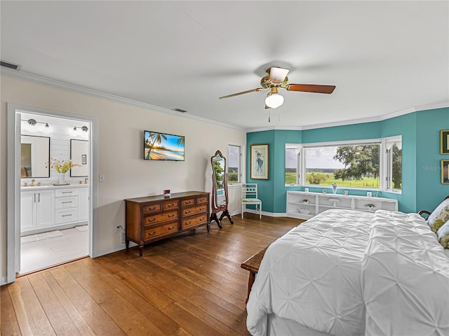 bedroom with ceiling fan, ensuite bath, dark wood-type flooring, and crown molding