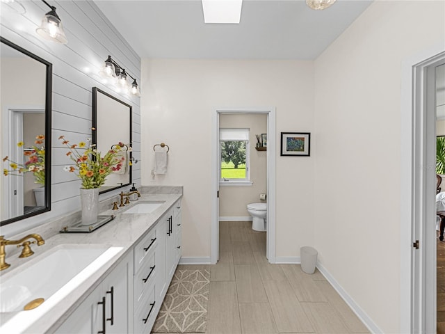 bathroom with toilet, vanity, and a skylight