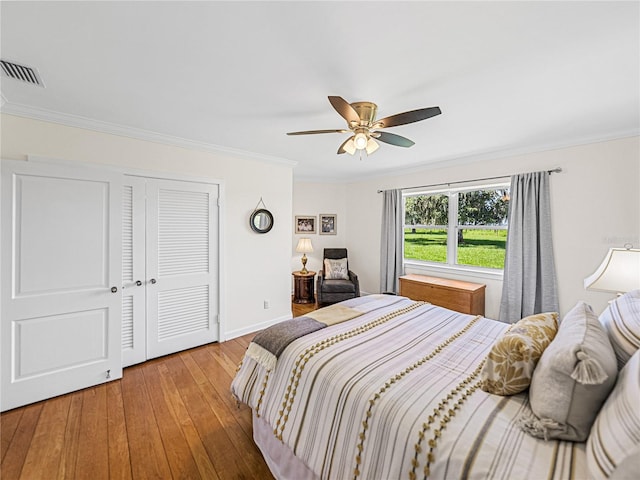 bedroom featuring ceiling fan, ornamental molding, a closet, and hardwood / wood-style floors