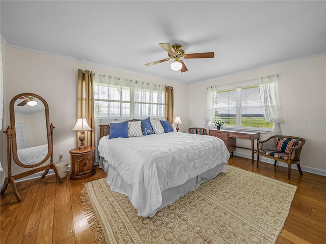 bedroom with ceiling fan, hardwood / wood-style flooring, and multiple windows