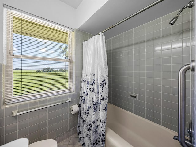 bathroom with toilet, tile walls, a wealth of natural light, and shower / bath combination with curtain