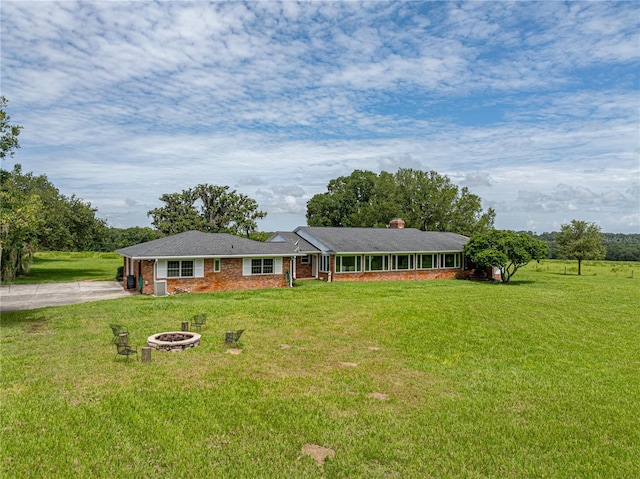 ranch-style house with an outdoor fire pit and a front lawn