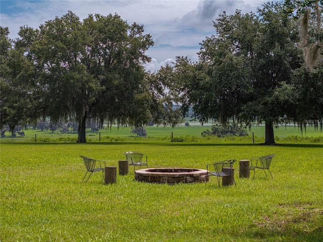 view of home's community with an outdoor fire pit and a lawn