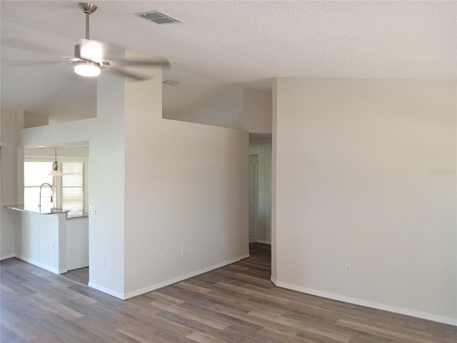 spare room with sink, vaulted ceiling, dark hardwood / wood-style floors, ceiling fan, and a textured ceiling