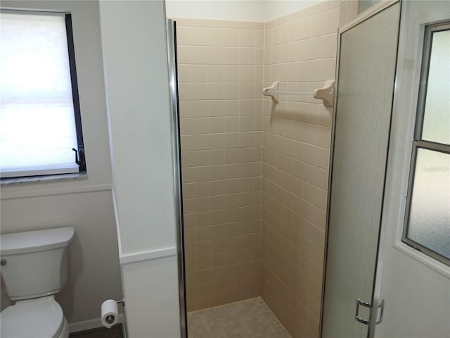 bathroom featuring toilet and a shower with shower door