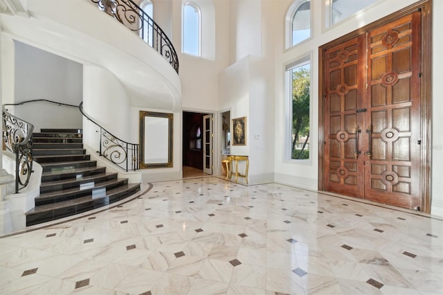 entrance foyer with a high ceiling, a healthy amount of sunlight, baseboards, and stairs