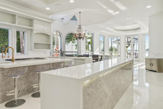 kitchen with a tray ceiling, light countertops, a large island, and recessed lighting