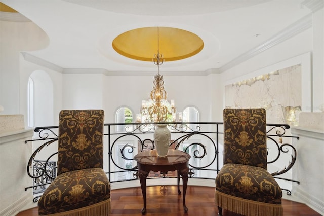 sitting room with a chandelier, ornamental molding, and wood finished floors