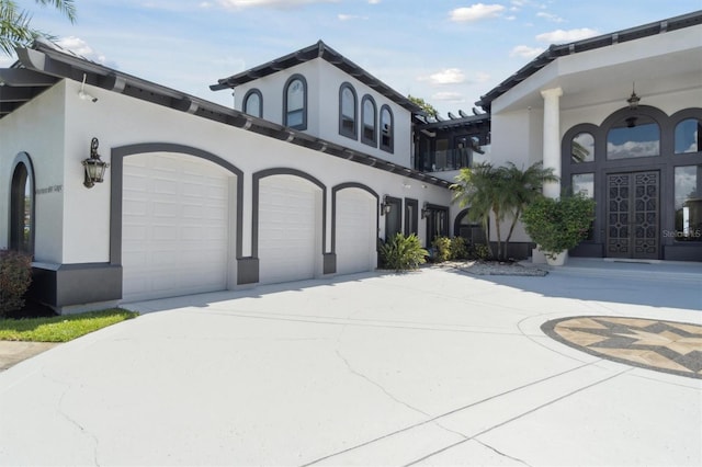 exterior space with an attached garage, french doors, concrete driveway, and stucco siding