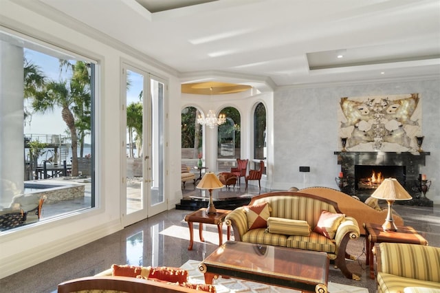 sunroom / solarium featuring a large fireplace, a raised ceiling, a notable chandelier, and french doors