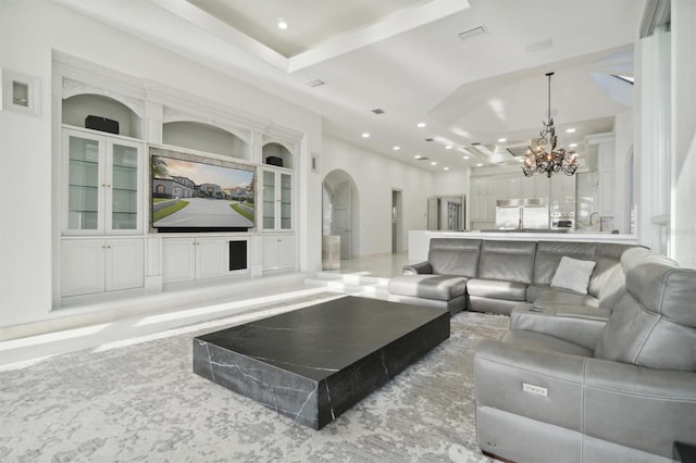 living room with built in shelves, arched walkways, a chandelier, and recessed lighting