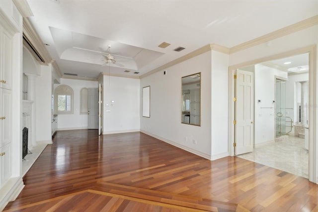 spare room featuring a raised ceiling, a fireplace, wood finished floors, and visible vents