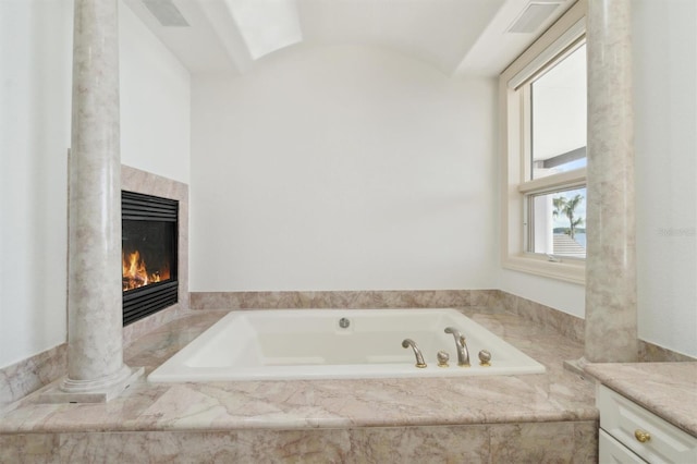 full bath featuring a garden tub, vanity, and a tiled fireplace