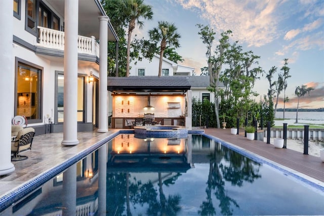 pool at dusk featuring a pool with connected hot tub