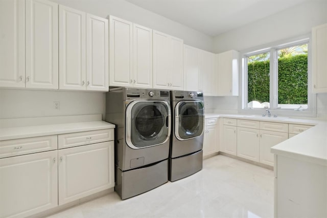 washroom with cabinet space, a sink, and washer and clothes dryer