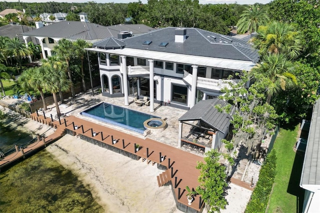 rear view of property featuring a balcony, an outdoor pool, and a patio