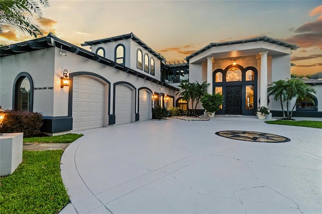 view of front of property featuring concrete driveway, an attached garage, and stucco siding