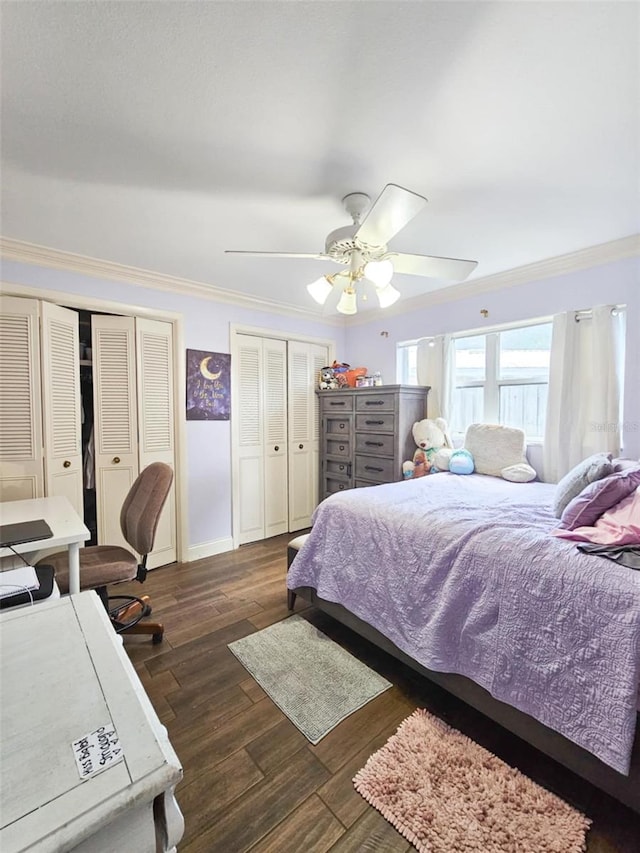 bedroom with ceiling fan, dark hardwood / wood-style flooring, ornamental molding, and two closets