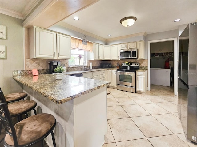 kitchen with backsplash, sink, a kitchen breakfast bar, stainless steel appliances, and light stone counters